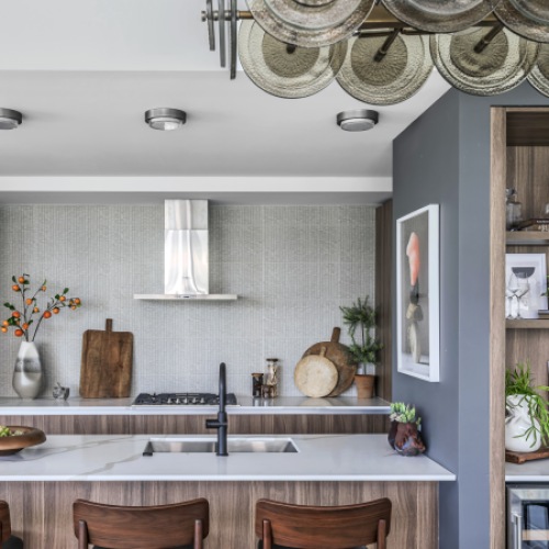 Contemporary kitchen featuring rich wood cabinetry, statement lighting, and a waterfall-edge island designed for elevated everyday living.