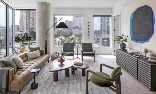Model apartment living room with designer furnishings, floor-to-ceiling windows, and city views at 2811 Maple