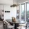 Model apartment dining area with sculptural chandelier, modern furniture, and private balcony access at 2811 Maple