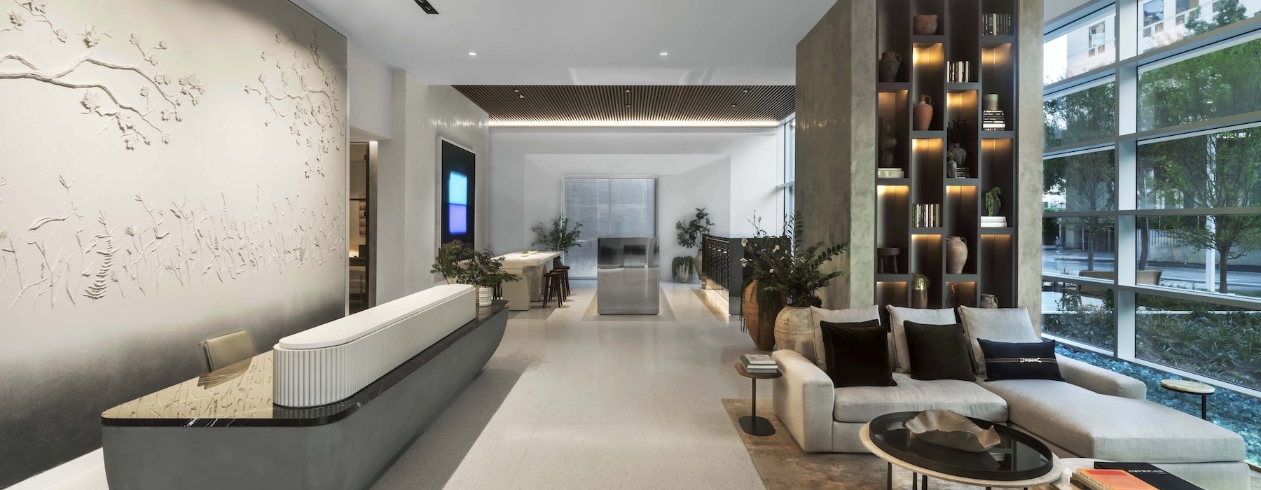 a lobby with a front desk, seating and large windows
